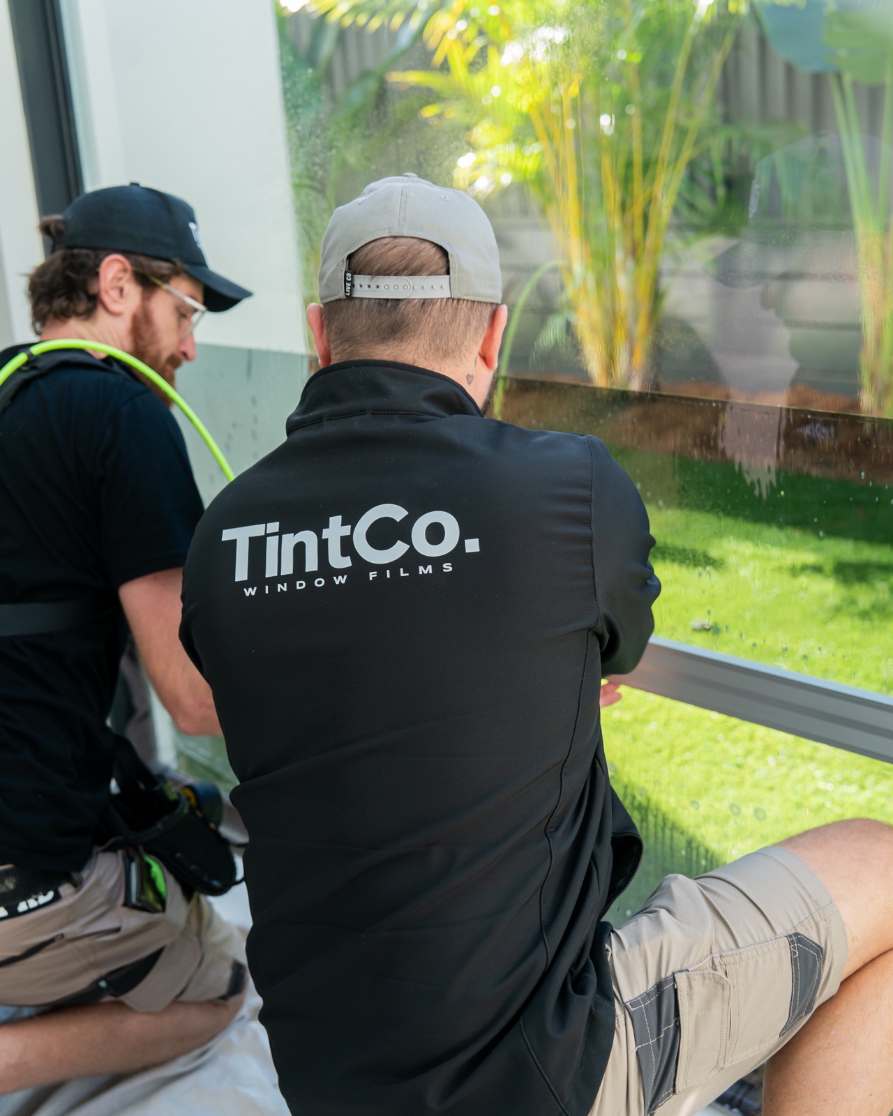 Two TintCo installers applying frosted film